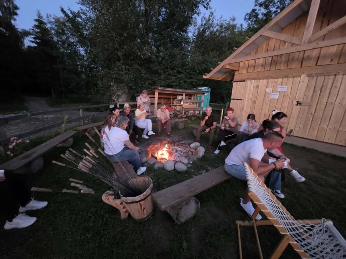 Goście przy ognisku w szałasie po zmroku
