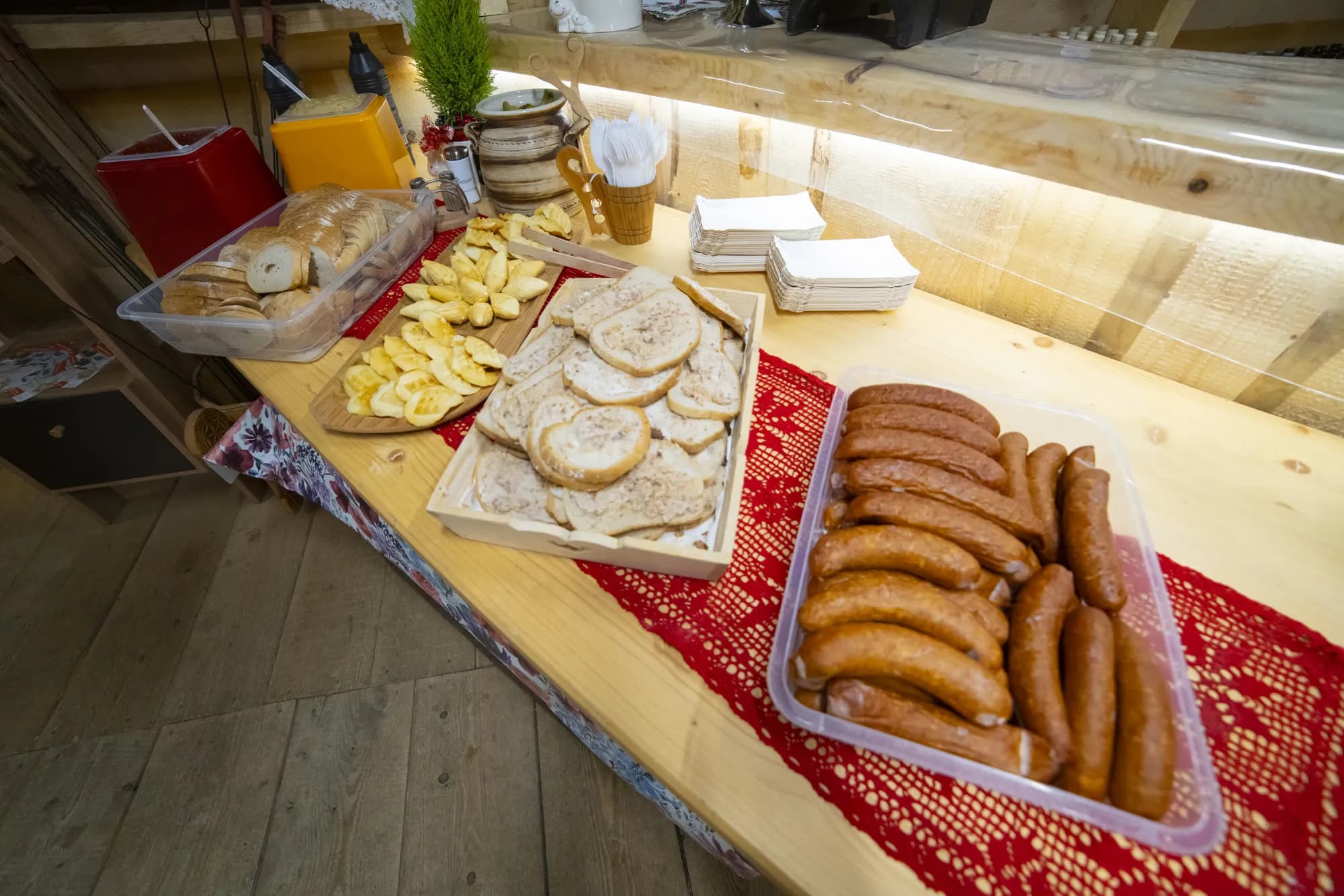 Kiełbaski, chleb ze smalcem i ogórki na stole biesiadnym