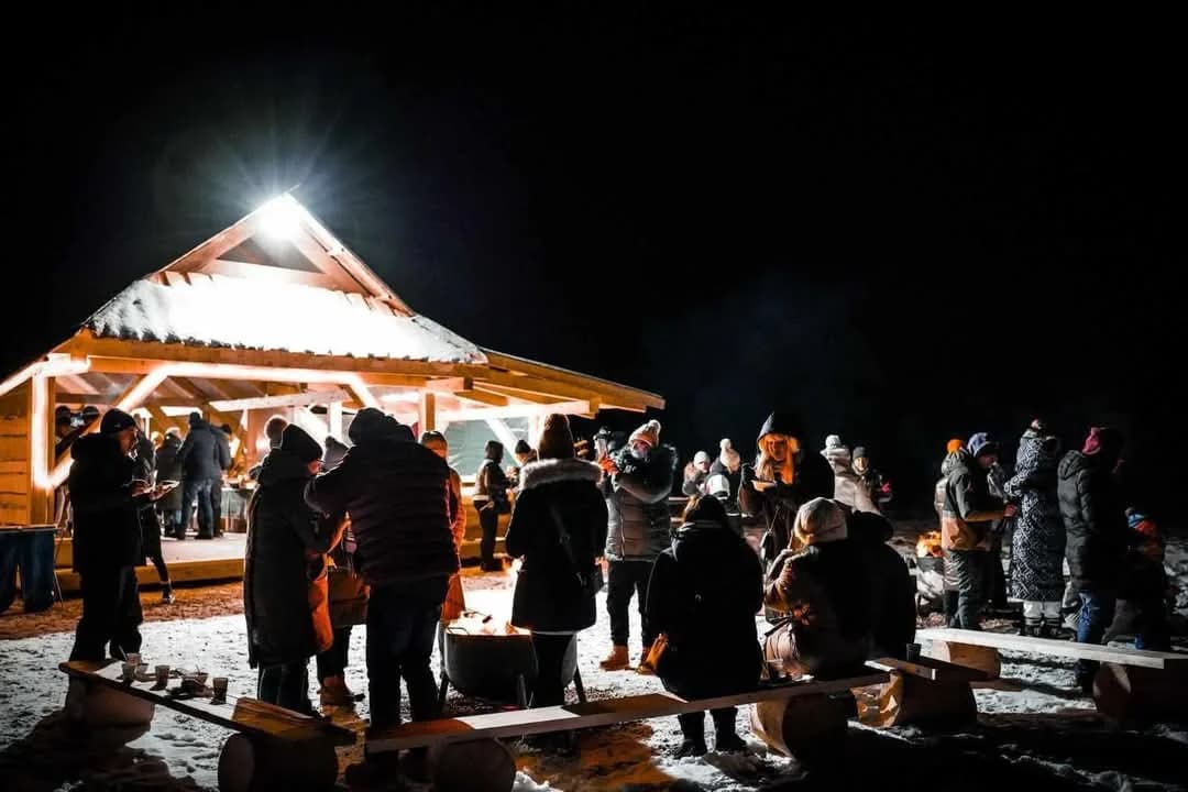Goście przy ognisku pod oświetloną bacówką w nocy